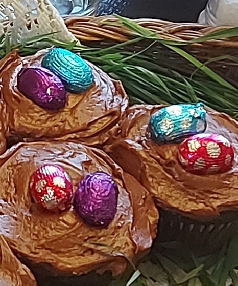 Chcolate Cupcakesnwith foil wrapped chocolate easter egss on top, all sitting on top of grass as a display